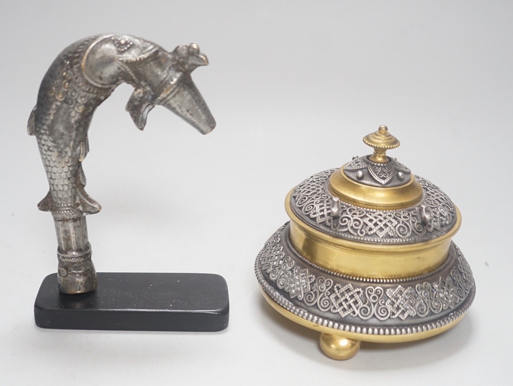 A Continental silvered and gilt metal inkwell, c.1900, and an Indo-Persian silvered bronze ‘fish’ tap or cane handle on stand, 16cm